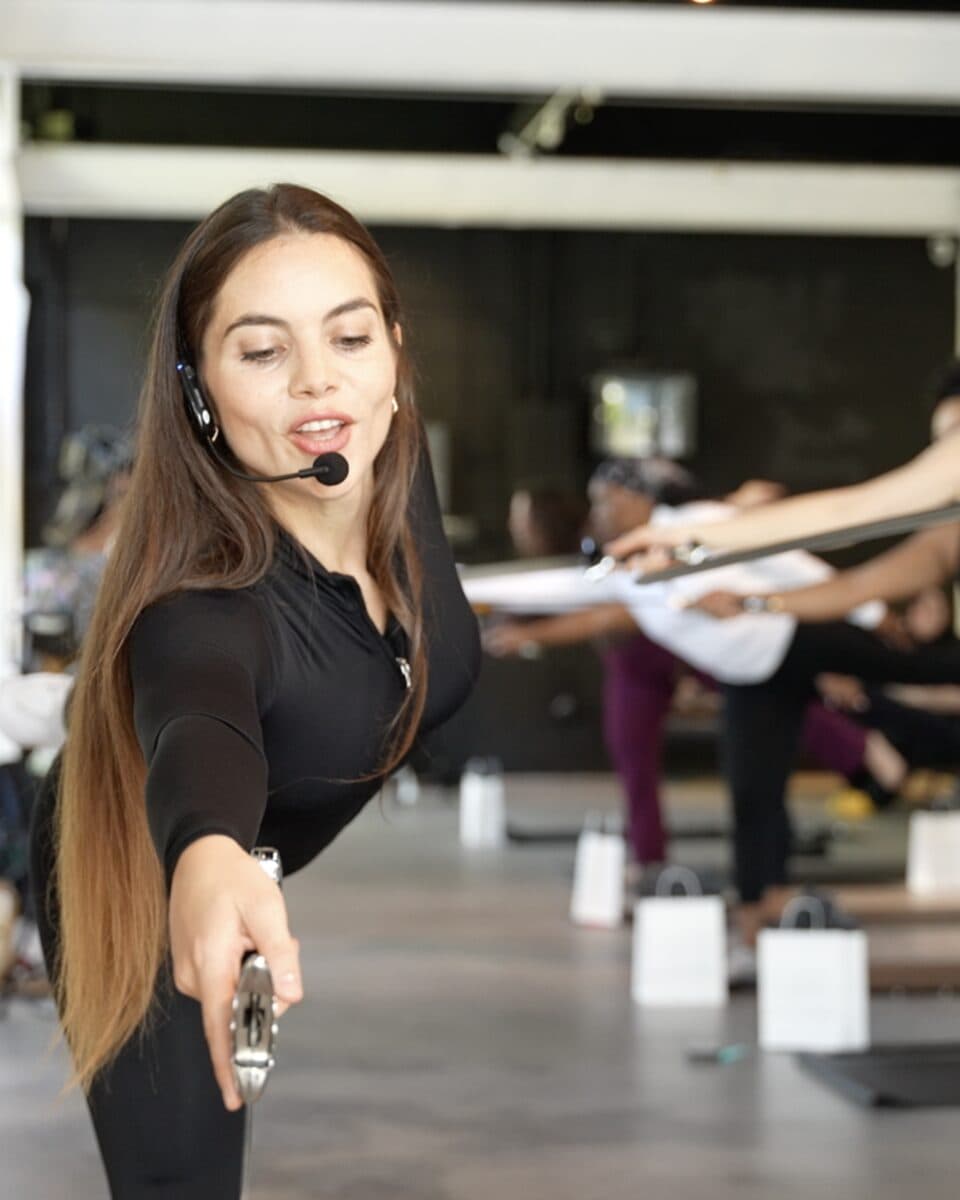 An instructor with a headset microphone teaching a WeaponUp class with her sword